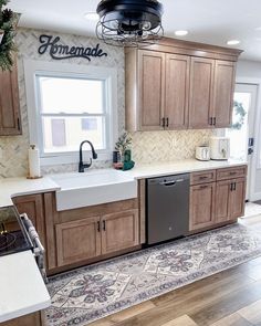 a kitchen with wooden cabinets and white counter tops, an oven, dishwasher, sink and window