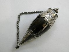 an antique silver plated metal object with chain around the neck on a white surface