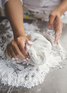 a person kneading flour on top of a table