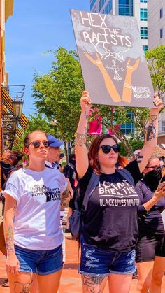 two women holding up signs in the middle of a street with other people behind them