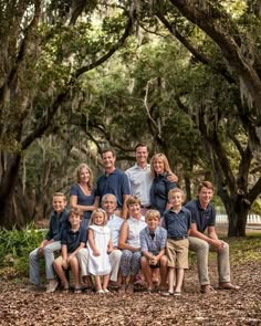 a family posing for a photo in front of trees with spanish moss on the ground