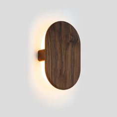 a wooden wall light that is on the side of a white wall with a circular light in front of it