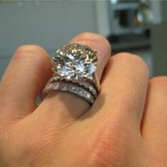 a close up of a person's hand holding a diamond ring