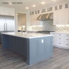 an instagramted photo of a kitchen with white cabinets and blue island tops,