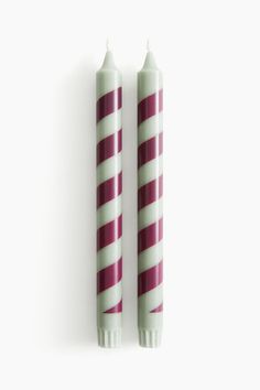 two candles sitting next to each other on a white surface with red and white stripes