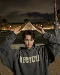 a young man is standing in front of the eiffel tower with his hands on his head