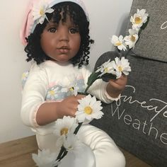 a doll is holding daisies in her hands