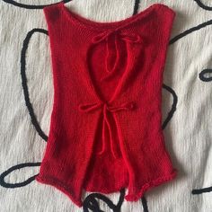 a red sweater with a knot on the front is laying on top of a bed