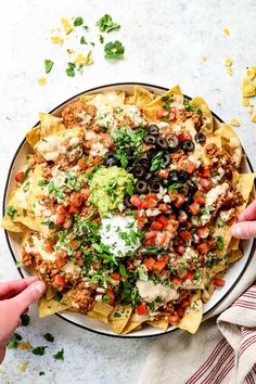 a plate filled with nachos topped with meat, cheese and salsa next to a napkin