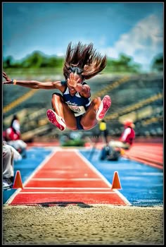 a woman jumping over an obstacle on a track