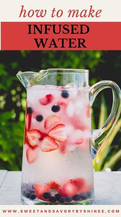 a pitcher filled with berries and ice sitting on top of a table next to plants