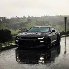 a chevrolet camaro is driving down the road in the rain