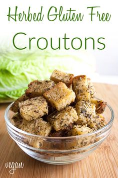 a bowl filled with croutons sitting on top of a wooden table next to lettuce