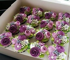 cupcakes decorated with purple and white flowers in a box