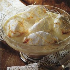 a glass bowl filled with food sitting on top of a wooden table next to a lace doily