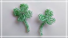 two green beaded shamrocks sitting next to each other