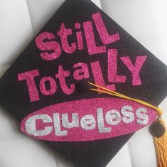 a black and pink graduation cap with the words still totally clueless written on it