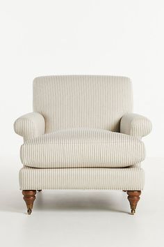 an upholstered chair with wooden legs and arm rests on a plain white surface