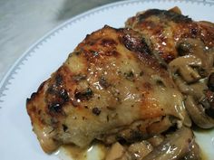 a white plate topped with meat covered in mushroom gravy on top of a table