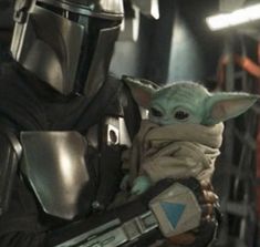 a baby yoda is holding the arm of someone else