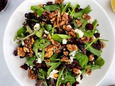 a white plate topped with greens and walnuts