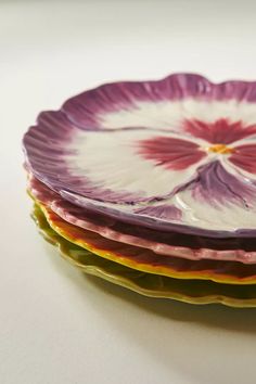 three purple and yellow plates stacked on top of each other in the shape of a flower