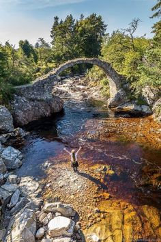 a man standing on rocks next to a river