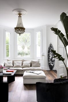 a living room filled with lots of furniture and a chandelier hanging from the ceiling