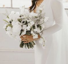 a woman holding a bouquet of white flowers