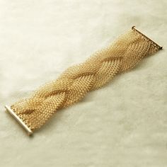 a gold bracelet is laying on a white surface