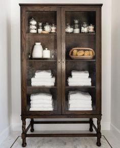 a wooden cabinet with glass doors filled with white towels