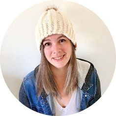 a woman wearing a white knitted hat in front of a white wall and smiling