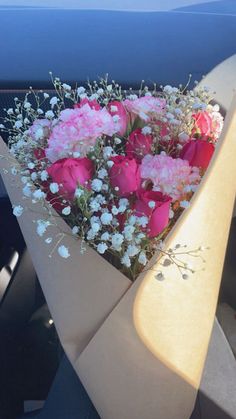 a bouquet of pink and white flowers sitting in the back seat of a car