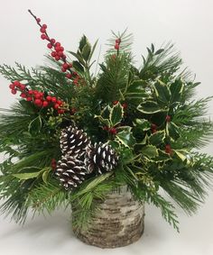 a christmas arrangement with pine cones, holly and berries