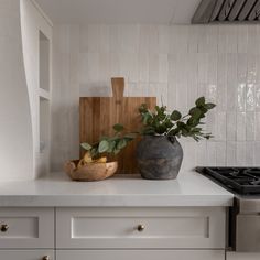 a cutting board sitting on top of a kitchen counter next to a potted plant