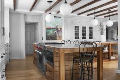 a large kitchen with an island in the middle and two stools at the counter