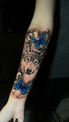 a woman's arm with a wolf and butterfly tattoo on it