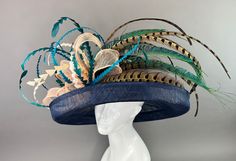 Navy Blue flipped brim hat adorned with peacock spines. Coordinated with shades of teal and turquoise feathers. Fits crown size of 22.5" with internal elastic band to create a snug and comfortable fit for crown sizes smaller than 22.5". Please measure prior to purchasing as all sales are final. Don't forget to follow us on Instagram @ TheHatHive Blue Feathered Hat For Races, Blue Summer Hat With Feather Trim, Blue Adjustable Hat With Feather Trim, Blue Feathered Costume Hat, Adjustable Blue Hat With Feather Trim, Blue Summer Hat With Feathers, Blue Summer Hats With Feathers, Blue Feathered Summer Hat, Summer Blue Hat With Feathers