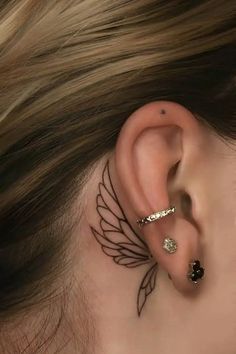 a woman's ear with an angel wing tattoo on her left behind the ear