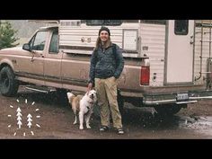 a woman standing next to two dogs in front of a truck