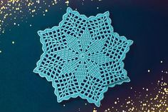 a crocheted doily on a blue surface with gold speckles around it