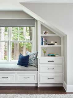 a window seat in the corner of a room with bookshelves and pillows on it