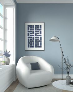 a white chair sitting in front of a window next to a table with a lamp on it