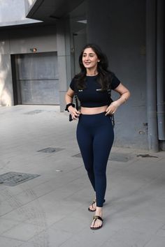 a woman in black top and leggings posing for the camera