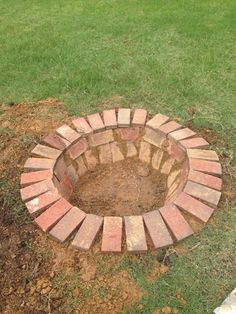 a brick fire pit sitting on top of a lush green field