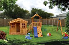 a wooden playset with slide and swings in the grass next to a fenced yard