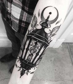 a person with a tattoo on their arm holding a lantern and an arrow in it