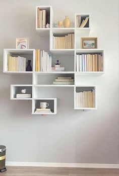 a white shelf filled with lots of books on top of a hard wood floor next to a wall