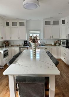 a large kitchen with white cabinets and marble counter tops, along with an island in the middle