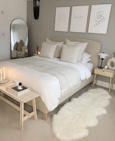 a white bed sitting in a bedroom next to a mirror